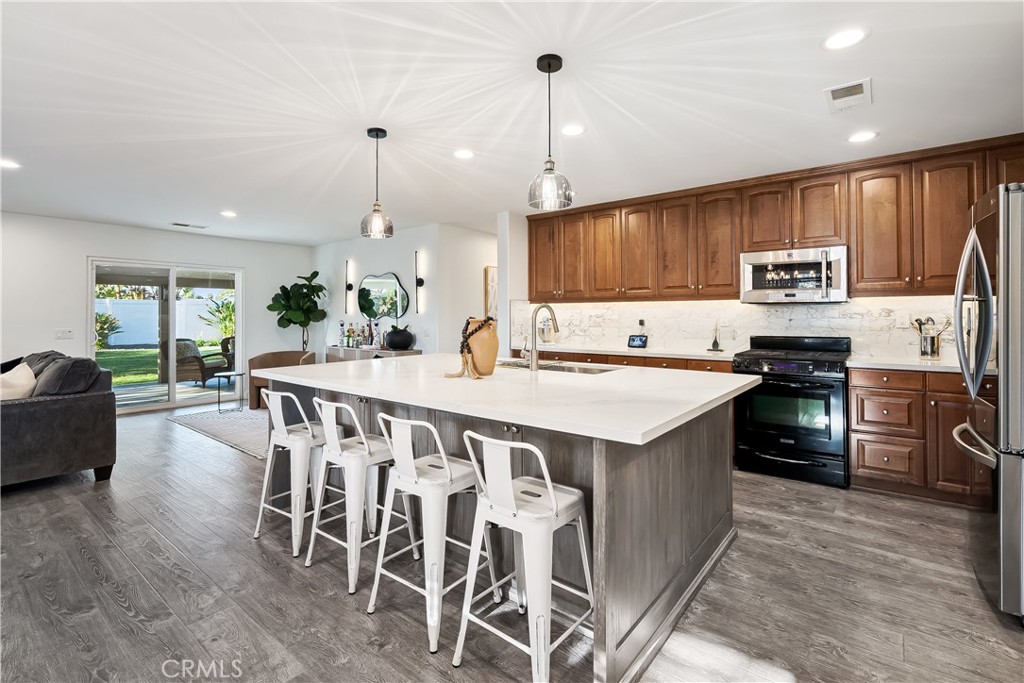 14428 Table Bluff Circle Eastvale, CA 92880 - Photo 15 of 29 a kitchen with stainless steel appliances kitchen island granite countertop a stove a sink and a refrigerator