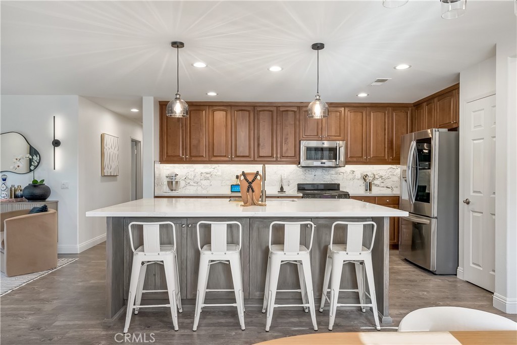 14428 Table Bluff Circle Eastvale, CA 92880 - Photo 16 of 29 a kitchen with stainless steel appliances granite countertop a dining table chairs refrigerator and microwave