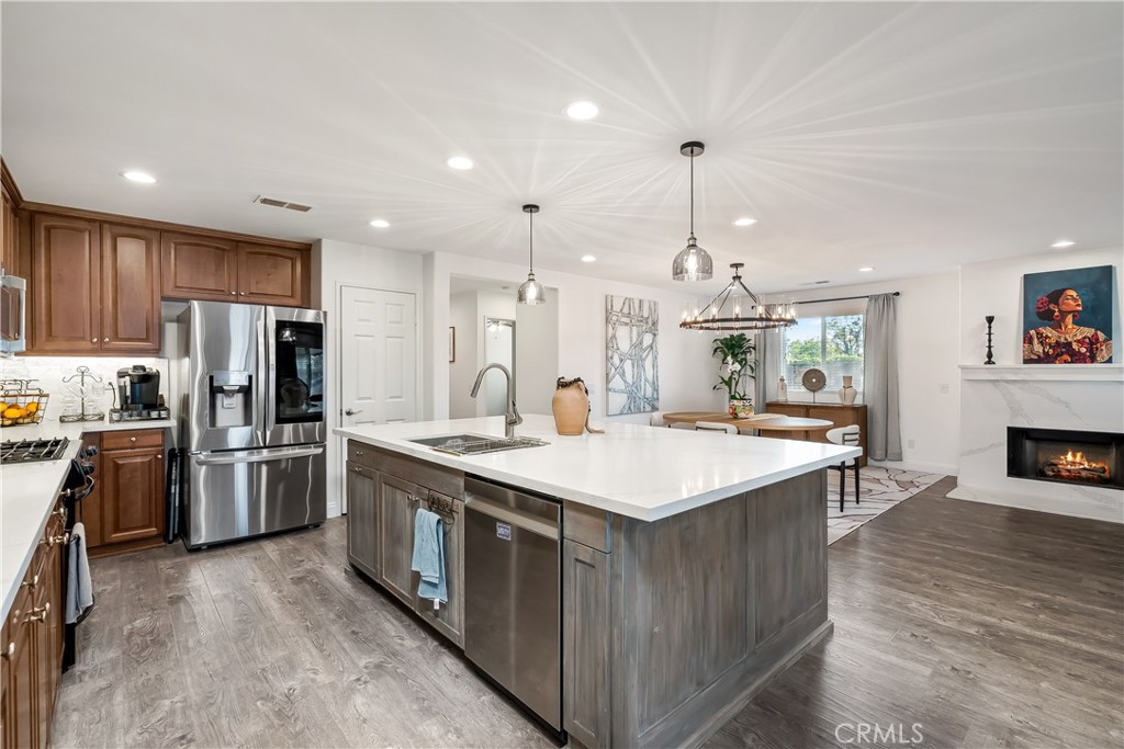 14428 Table Bluff Circle Eastvale, CA 92880 - Photo 17 of 29 a large kitchen with kitchen island a stove a sink a refrigerator and a dining table with wooden floor