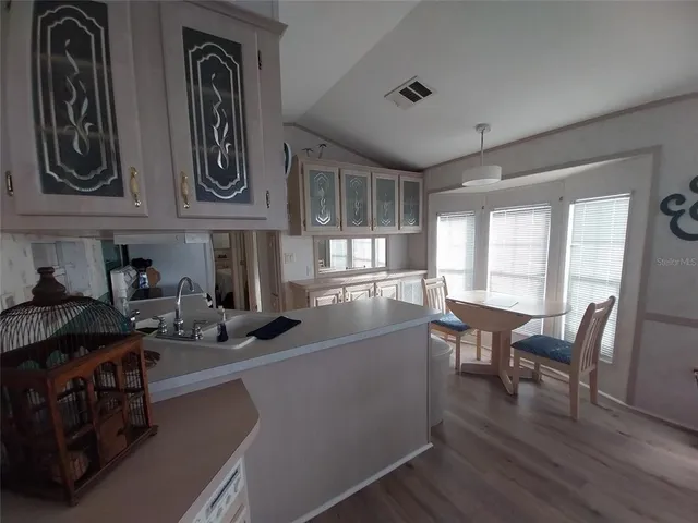 a kitchen with stainless steel appliances granite countertop a refrigerator a stove top oven a dining table and chairs with wooden floor