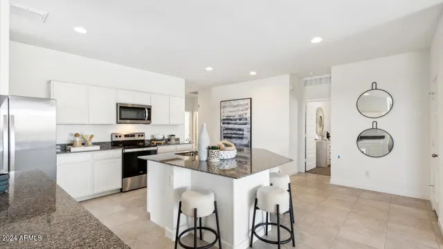 a kitchen with stainless steel appliances granite countertop a stove top oven a sink dishwasher and a refrigerator with wooden floor