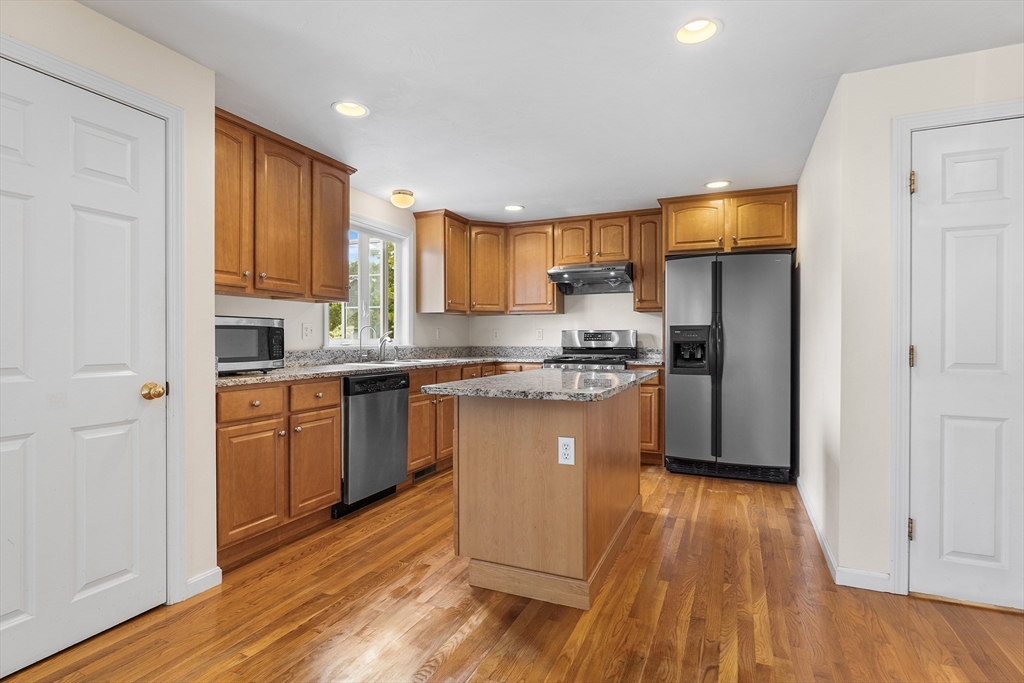 70 Loring Avenue Boxborough, MA 01719 - Photo 6 of 33 a kitchen with granite countertop wooden floors a refrigerator a sink and white cabinets