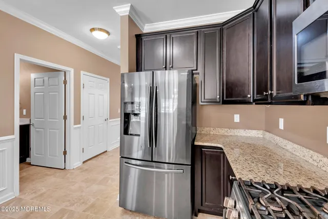 a kitchen with kitchen island stainless steel appliances a dining table chairs and white cabinets