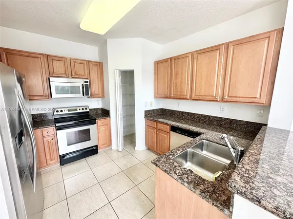 a kitchen with stainless steel appliances granite countertop a stove a sink and a microwave