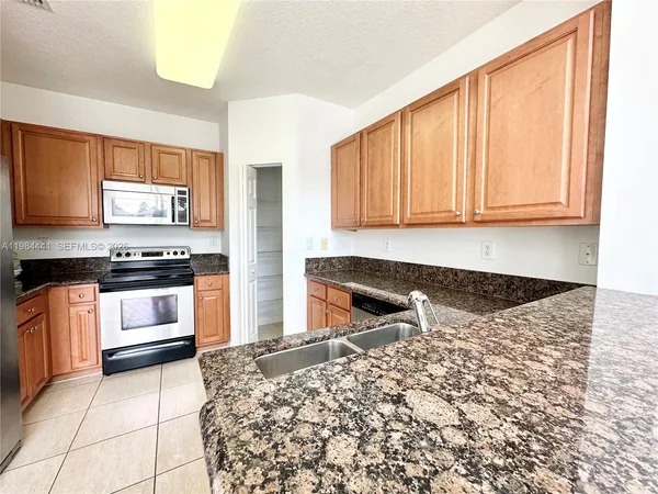 a kitchen with granite countertop white cabinets and stainless steel appliances