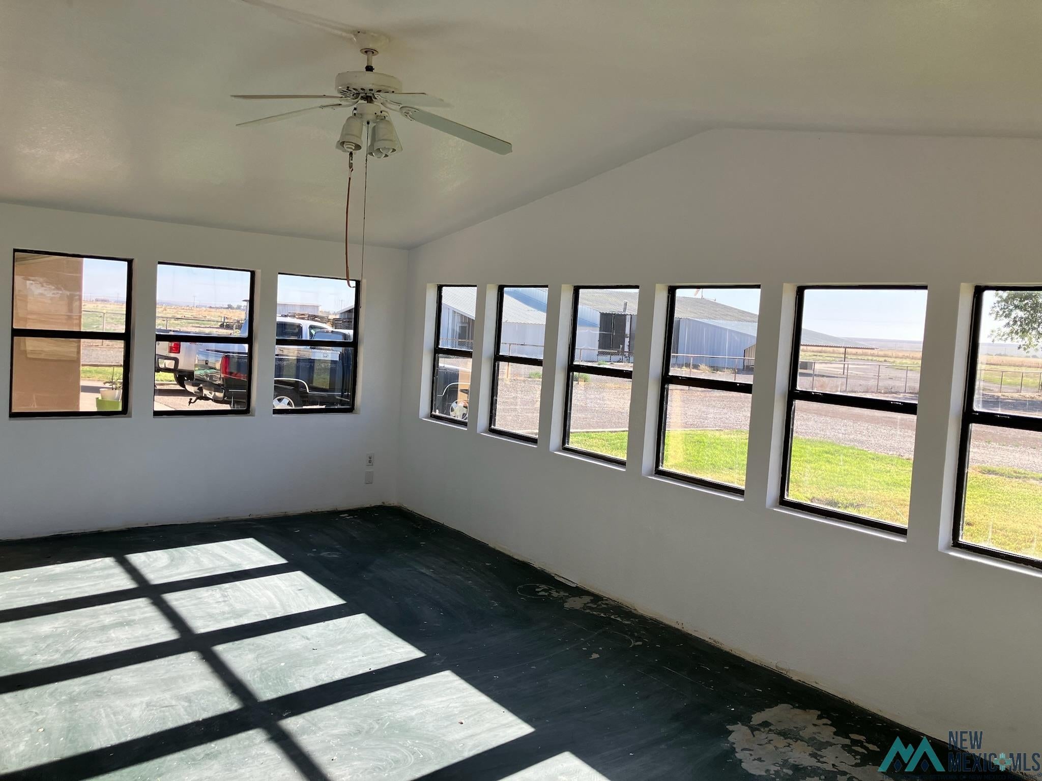 6660 Cherokee Road Dexter, NM 88230 - Photo 7 of 46 Sunlit interior room featuring multiple large windows, a vaulted ceiling, and a ceiling fan with integrated lighting