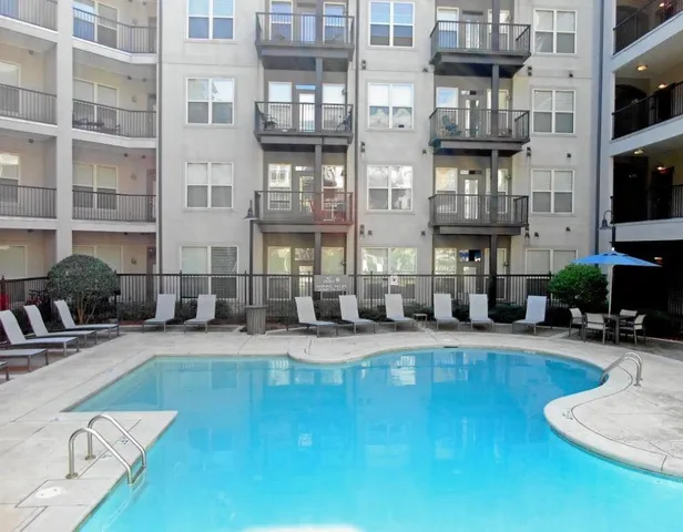 a living room with couches chairs and kitchen view with wooden floor