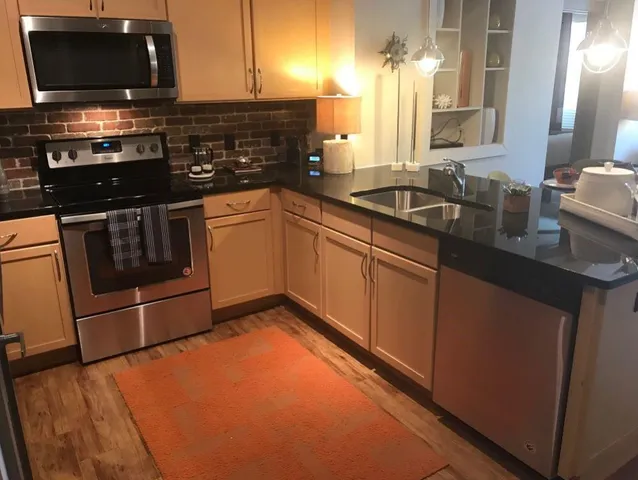 a kitchen with stainless steel appliances granite countertop a stove a sink and a microwave