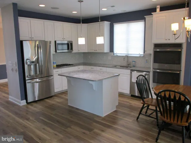 a kitchen with kitchen island granite countertop a sink a counter space appliances and cabinets