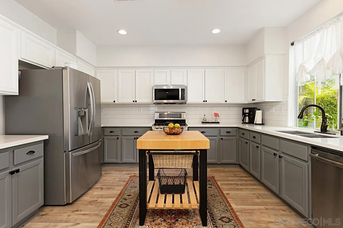 1058 Bells Drive Oceanside, CA 92057 - Photo 14 of 31 a kitchen with stainless steel appliances a stove refrigerator sink and microwave