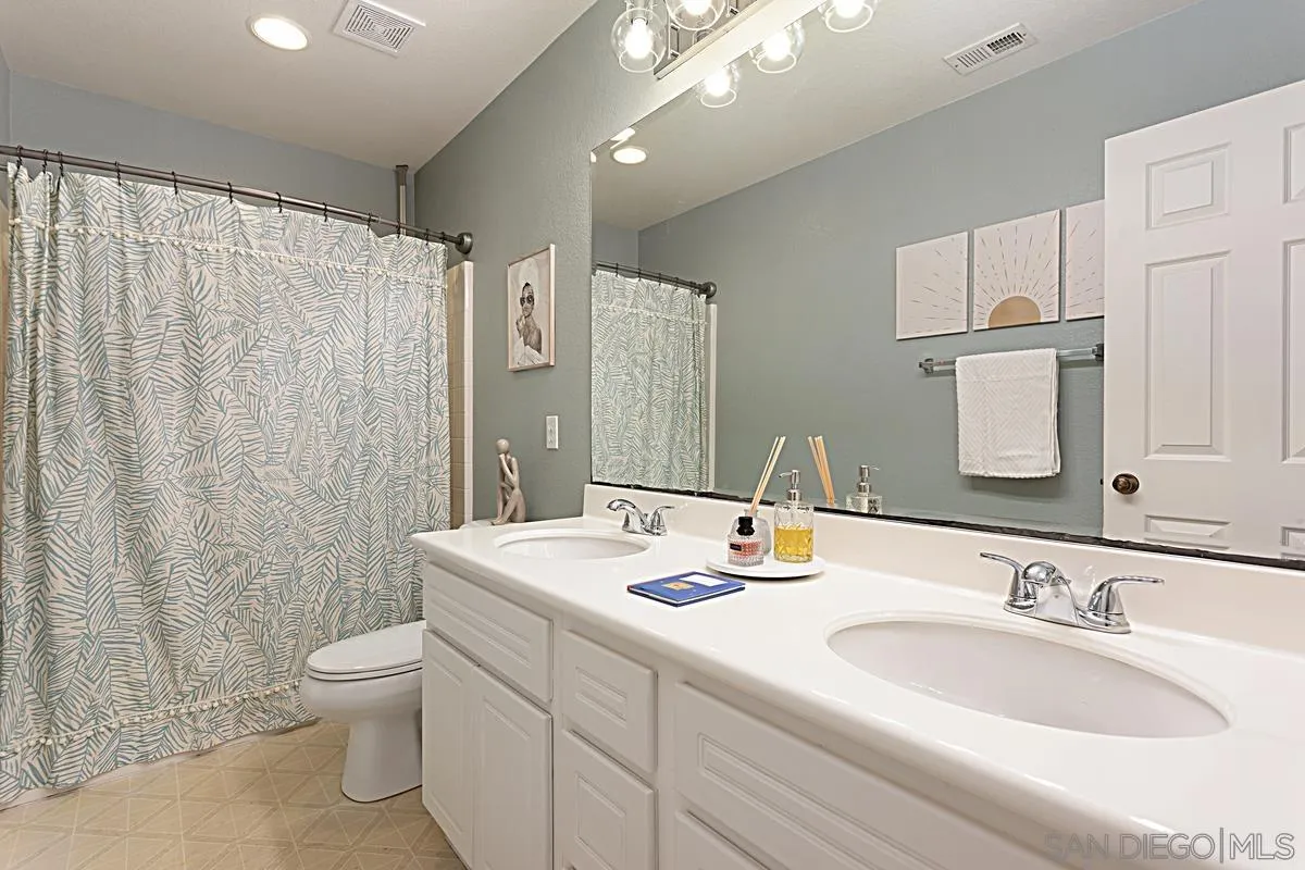 1058 Bells Drive Oceanside, CA 92057 - Photo 25 of 31 a bathroom with a double vanity sink toilet and a mirror