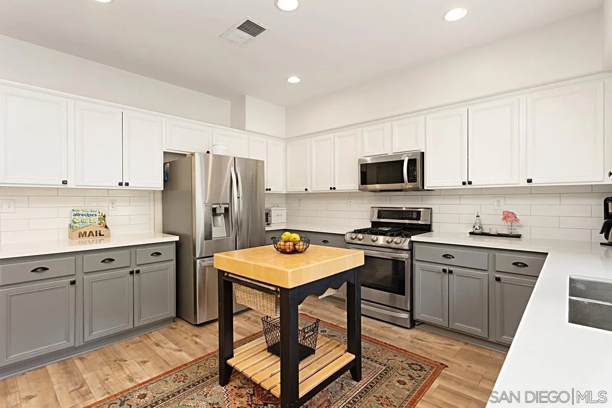1058 Bells Drive Oceanside, CA 92057 - Photo 3 of 31 a kitchen with stainless steel appliances granite countertop a stove top oven a refrigerator a sink and dishwasher a oven with white cabinets