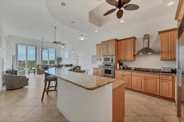 a kitchen with stainless steel appliances granite countertop a sink dishwasher stove top oven a dining table and chairs with wooden floor
