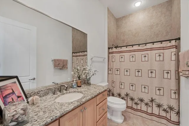 a bathroom with a granite countertop toilet sink and mirror