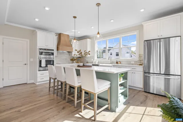 a kitchen with stainless steel appliances granite countertop a dining table chairs refrigerator and microwave