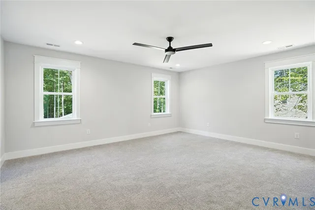 an empty room with chandelier fan and windows