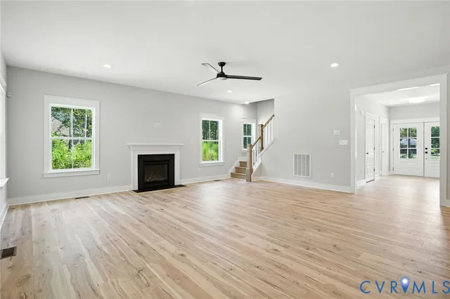 an empty room with wooden floor fireplace and windows