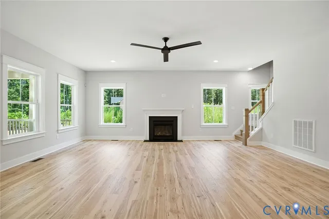 an empty room with windows a fireplace and wooden floor