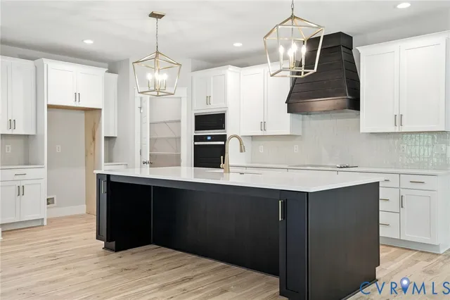 a kitchen with stainless steel appliances granite countertop a sink a stove a refrigerator and island with wooden floor