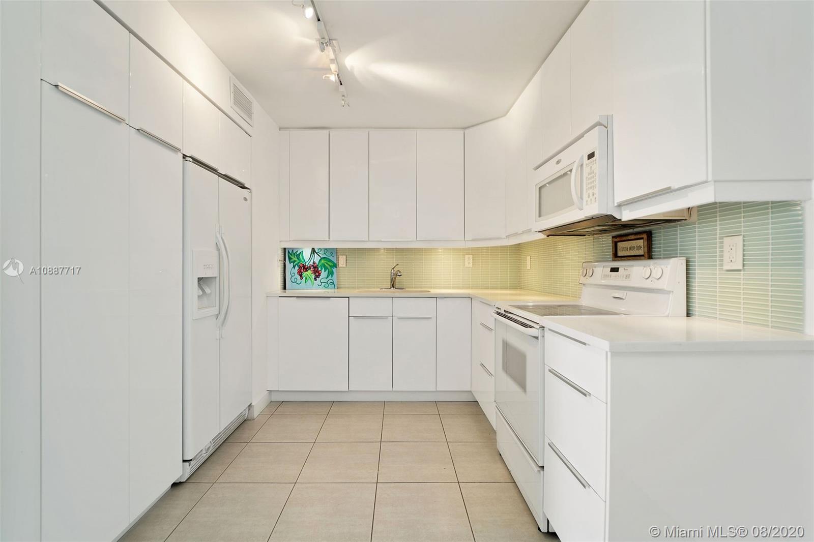 1450 Brickell Bay Drive, Unit 612 Miami, FL 33131 - Photo 3 of 25 a kitchen with white cabinets and white appliances