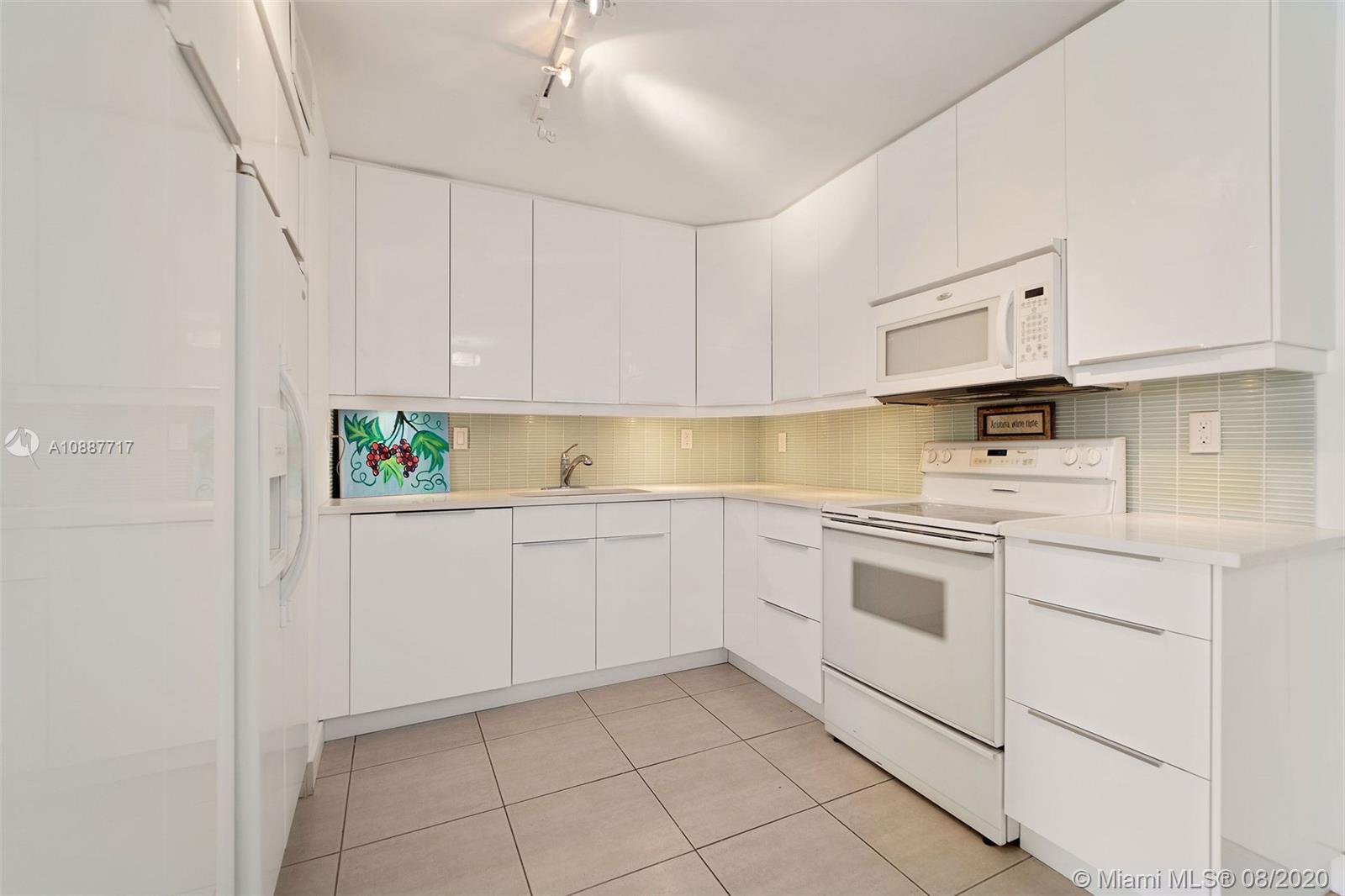 1450 Brickell Bay Drive, Unit 612 Miami, FL 33131 - Photo 4 of 25 a kitchen with granite countertop white cabinets stainless steel appliances and sink