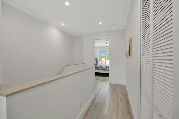 a view of a hallway to a livingroom with wooden floor a fireplace and a window