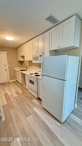 a kitchen with cabinets wooden floor and stainless steel appliances