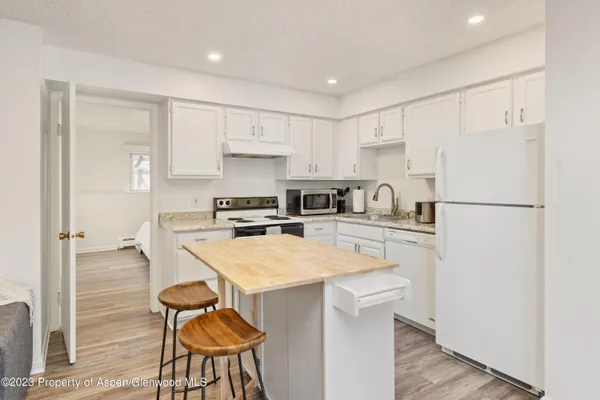 a kitchen with a refrigerator a stove a sink and a refrigerator with wooden floor