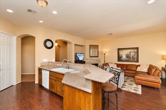 a living room with stainless steel appliances furniture a clock and a view of kitchen