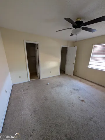 an empty room with ceiling fan and window