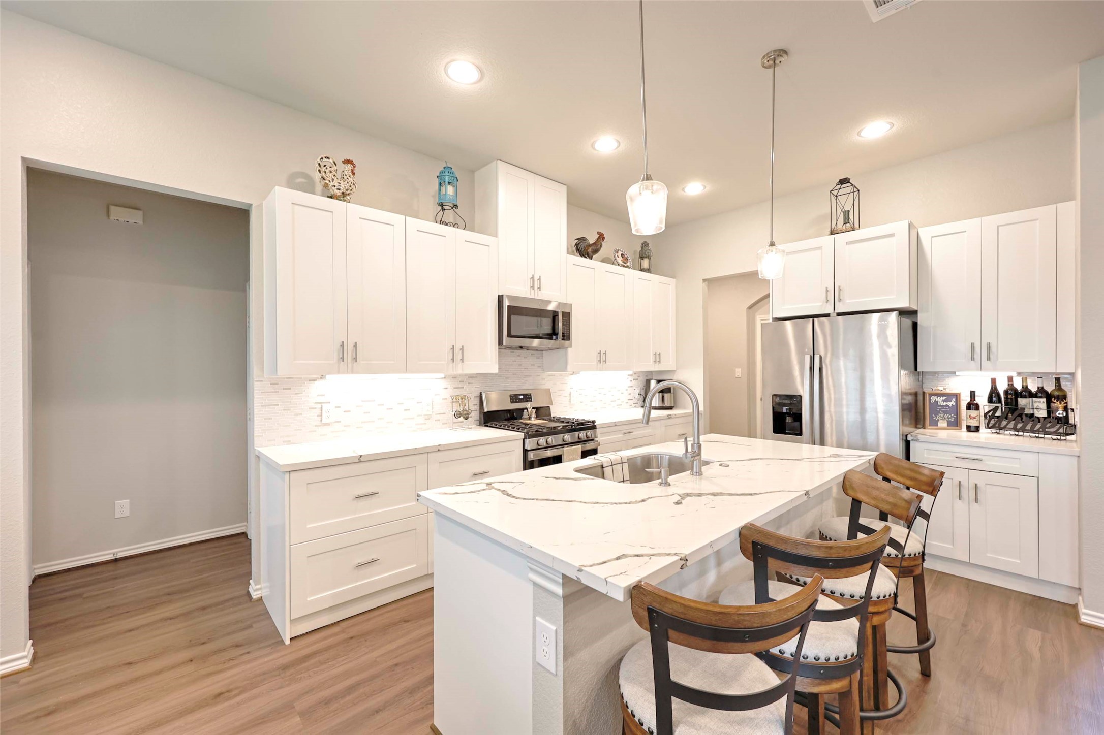 206 East Hinton Road Weimar, TX 78962 - Photo 7 of 22 Kitchen with a kitchen bar, white cabinets, stainless steel appliances, a center island with sink, and tasteful backsplash