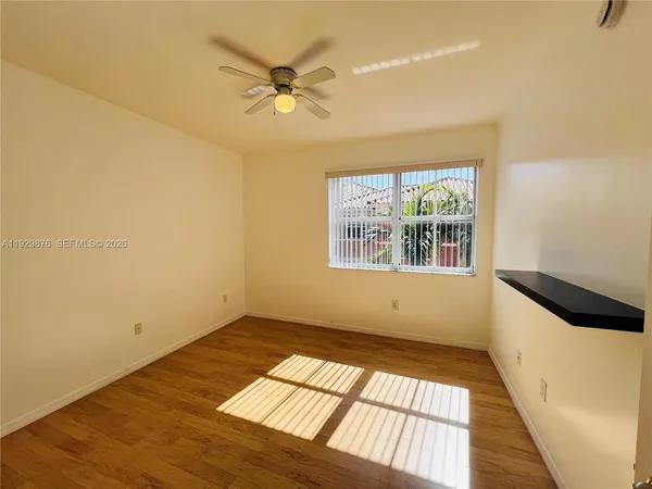 an empty room with wooden floor fan and windows