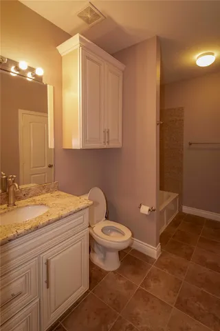 a bathroom with a granite countertop sink a toilet and a mirror