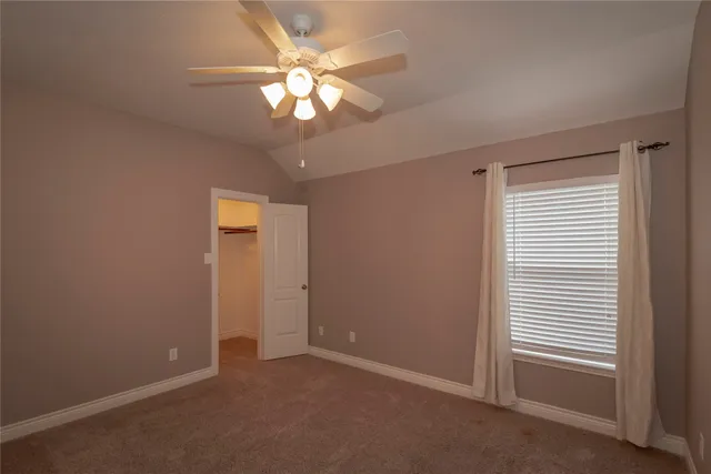 an empty room with a chandelier fan and windows