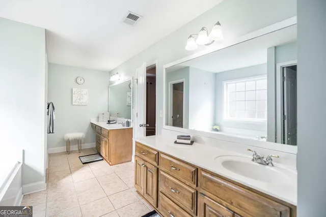 a spacious bathroom with a double vanity sink a large mirror and a bathtub