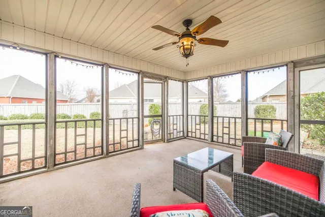 a living room with furniture floor to ceiling windows and a ceiling fan