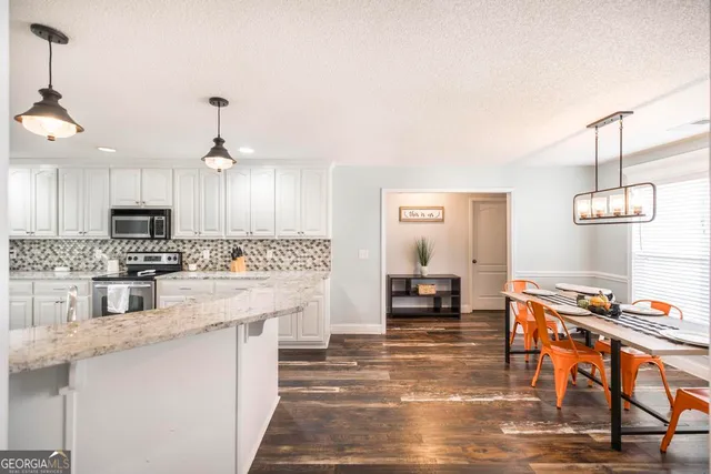 a kitchen with stainless steel appliances granite countertop a stove top oven a sink dishwasher and a dining table with kitchen view