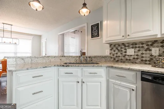 a kitchen with granite countertop white cabinets and a sink