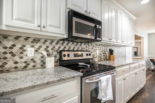 a kitchen with granite countertop white cabinets and stainless steel appliances
