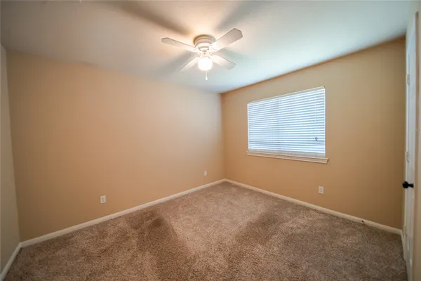 an empty room with a window and a fan