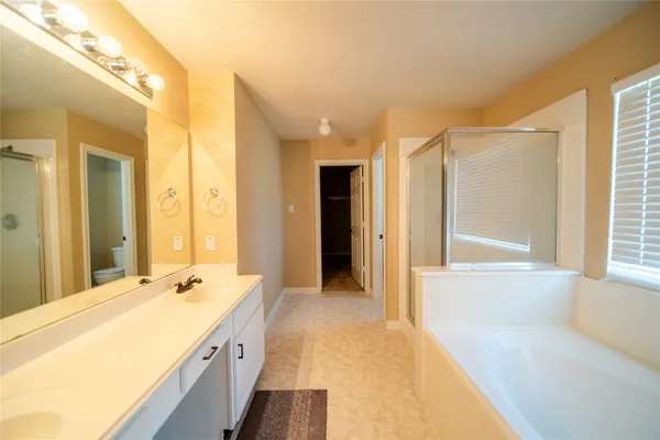 a spacious bathroom with a tub sink and mirror