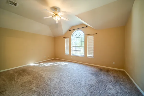 an empty room with windows and chandelier fan