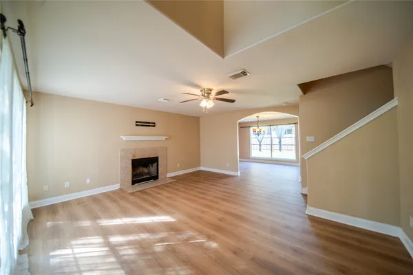 a view of an empty room with window and wooden floor