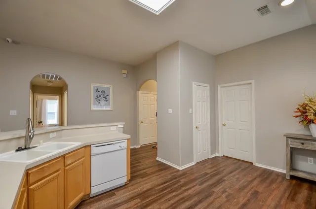 a kitchen with stainless steel appliances a sink a stove a refrigerator and white cabinets