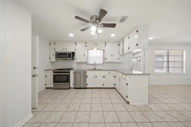 a kitchen with granite countertop a white stove top oven sink and cabinets
