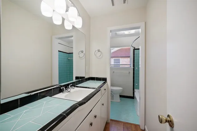 a bathroom with a granite countertop sink a toilet and mirror