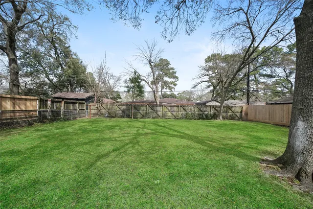 a view of a house with a yard and large trees