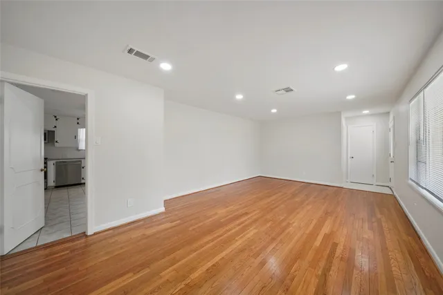a view of empty room with wooden floor and a kitchen
