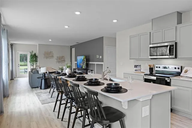a kitchen with a stove a kitchen island white cabinets and wooden floor