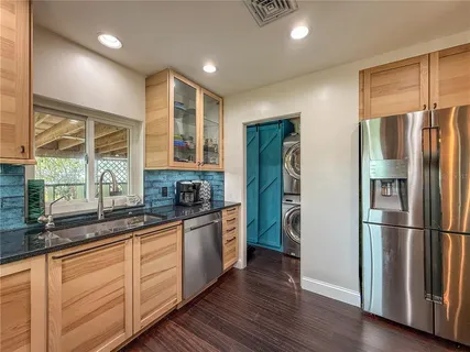 a kitchen with stainless steel appliances granite countertop a refrigerator a sink and wooden cabinets